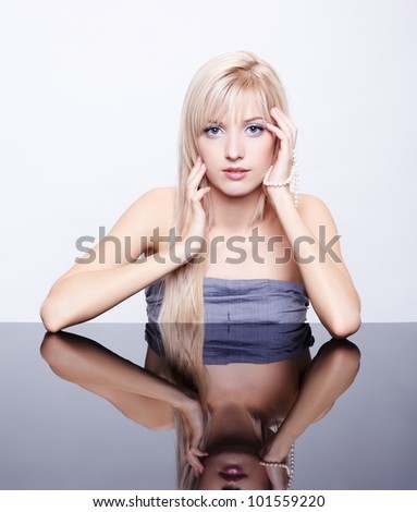 Portrait of young beautiful long-haired blonde woman sitting at mirror