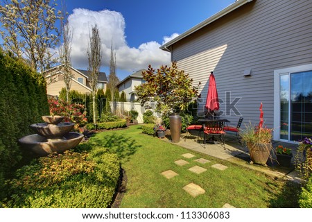 Spring house back yard with red chairs and umbrella and nice landscape 