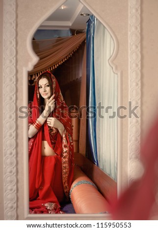 Beautiful Indian bride looking in mirror - stock photo