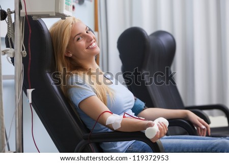 Smiling woman donating blood in hospital - stock photo