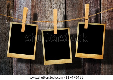 Old picture frame hanging on clothesline on wood background. stock 