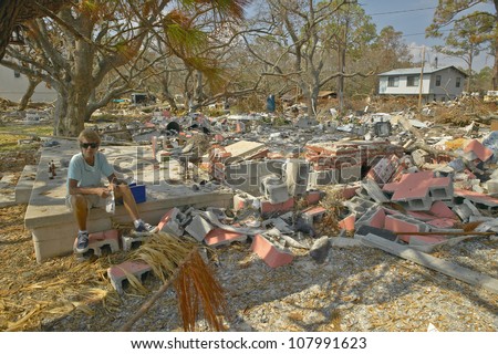  - stock-photo-lifetime-woman-resident-surveying-damage-and-debris-in-front-of-her-house-hit-by-hurricane-ivan-in-107991623