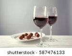 stock-photo-chocolate-truffles-and-glasses-with-red-wine-on-white-wooden-table-587476133.jpg