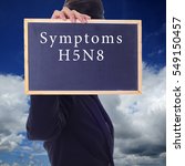 Small photo of A women holding a chalk board with word " SYMPTOMS H5N8 " isolated in a background of blue sky. H5N8 is a subtype of the Influenza A virus.