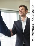 Small photo of Smiling young businessman wearing suit shaking male hand, greeting welcoming handshake at meeting, nice to meet you, good first impression, happy to join business team, thanking for support, vertical