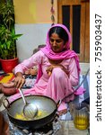 Small photo of Jodhpur, India - Nov 6, 2017. A woman cooking traditional food on street in Jodhpur, India. Jodhpur is a popular tourist destination, featuring many palaces, forts and temples.
