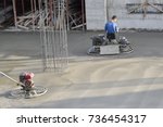 Small photo of Employee performs sand and cement screed floor with ride-on trowels with dual counter-rotating rotors "helicopters" with four blades on each rotor.