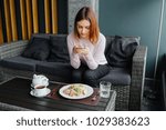 Small photo of Woman sitting on the couch ready to eat and talking picture to her food