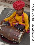 Small photo of Rajasthan, India - march 14, 2006: Young boy with typical rajastani clothes playing a bongo at the entrance gate to Jodhpur Fort