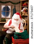 Small photo of Santa Claus Sitting in His Workshop taking a letter from a mailbag. Vertical Composition.