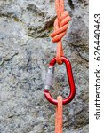 Small photo of carabiner with rope on rocky background. Climbing uquipment