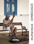 Small photo of Panama City, Panama - 05/27/2017: A banjo-playing busker sitting behind the Instituto Nacional de Cultura, near the touristy Plaza de Francia, in Casco Viejo.