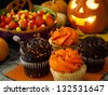 Halloween cupcakes with orange and black icing on orange napkin. - stock photo