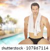 Portrait of a healthy good-looking guy in bathing suit with towel around his neck in beautiful spa resort setting - stock photo