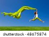 stock photo : Beautiful young woman jumping on  a green meadow with a colored tissue