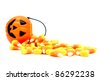 Pumpkin candy holder with spilling Halloween candy corn over white - stock photo