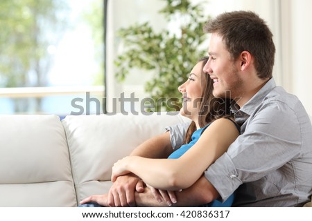 https://thumb10.shutterstock.com/display_pic_with_logo/1020994/420836317/stock-photo-side-view-of-a-happy-couple-hugging-sitting-on-a-couch-and-looking-outdoors-through-the-window-at-420836317.jpg