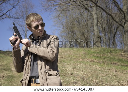 stock-photo-a-young-man-with-a-gun-in-a-field-of-dry-grass-634145087.jpg