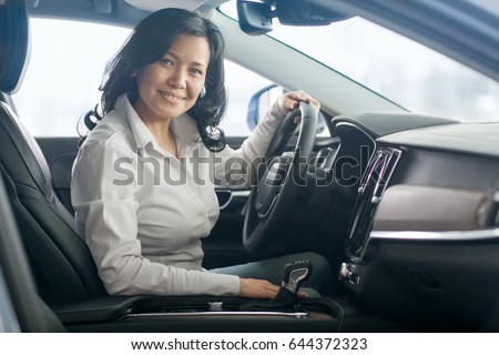 https://thumb10.shutterstock.com/display_pic_with_logo/175112680/644372323/stock-photo-happy-mature-asian-woman-smiling-to-the-camera-joyfully-sitting-in-a-car-at-the-dealership-showroom-644372323.jpg