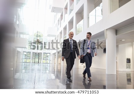 Businessmen Talking As They Walk Through Office Lobby