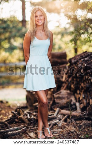 stock photo portrait of beautiful young blonde woman in front of pile of wood in dress legs crossed 240537487