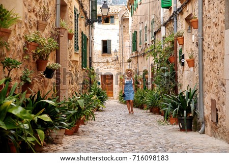 https://thumb10.shutterstock.com/display_pic_with_logo/3722837/716098183/stock-photo-beautiful-pretty-woman-walking-at-old-town-pavement-street-with-flowers-and-looking-away-travel-716098183.jpg