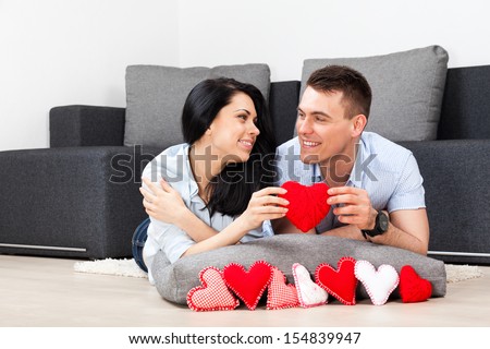 https://thumb10.shutterstock.com/display_pic_with_logo/534712/154839947/stock-photo-young-love-couple-holding-lot-of-red-valentine-s-heart-together-lying-on-couch-living-room-at-home-154839947.jpg